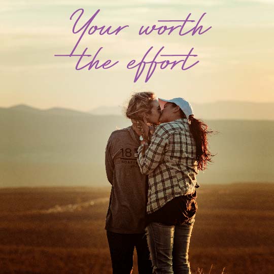 A couple embracing and kissing in an outdoor field at sunset, with purple script text reading 'Your worth the effort' overlaid at the top.